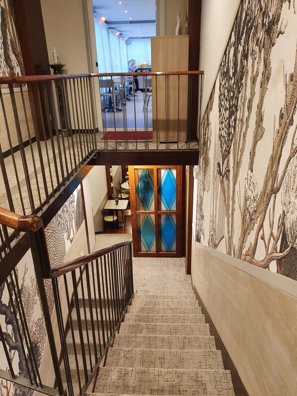 A staircase with a wooden railing and a glass door with blue diamond-shaped panes. - Hotel Corallo (La Spezia)