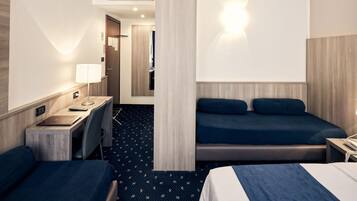 Ein Hotelzimmer mit zwei Betten, einem Schreibtisch mit Lampe, einem Telefon und einer kleinen Sitzecke.
