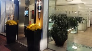 A modern interior with a reception desk, a large potted plant, and a glass partition. - Hotel Roberta (Mestre)