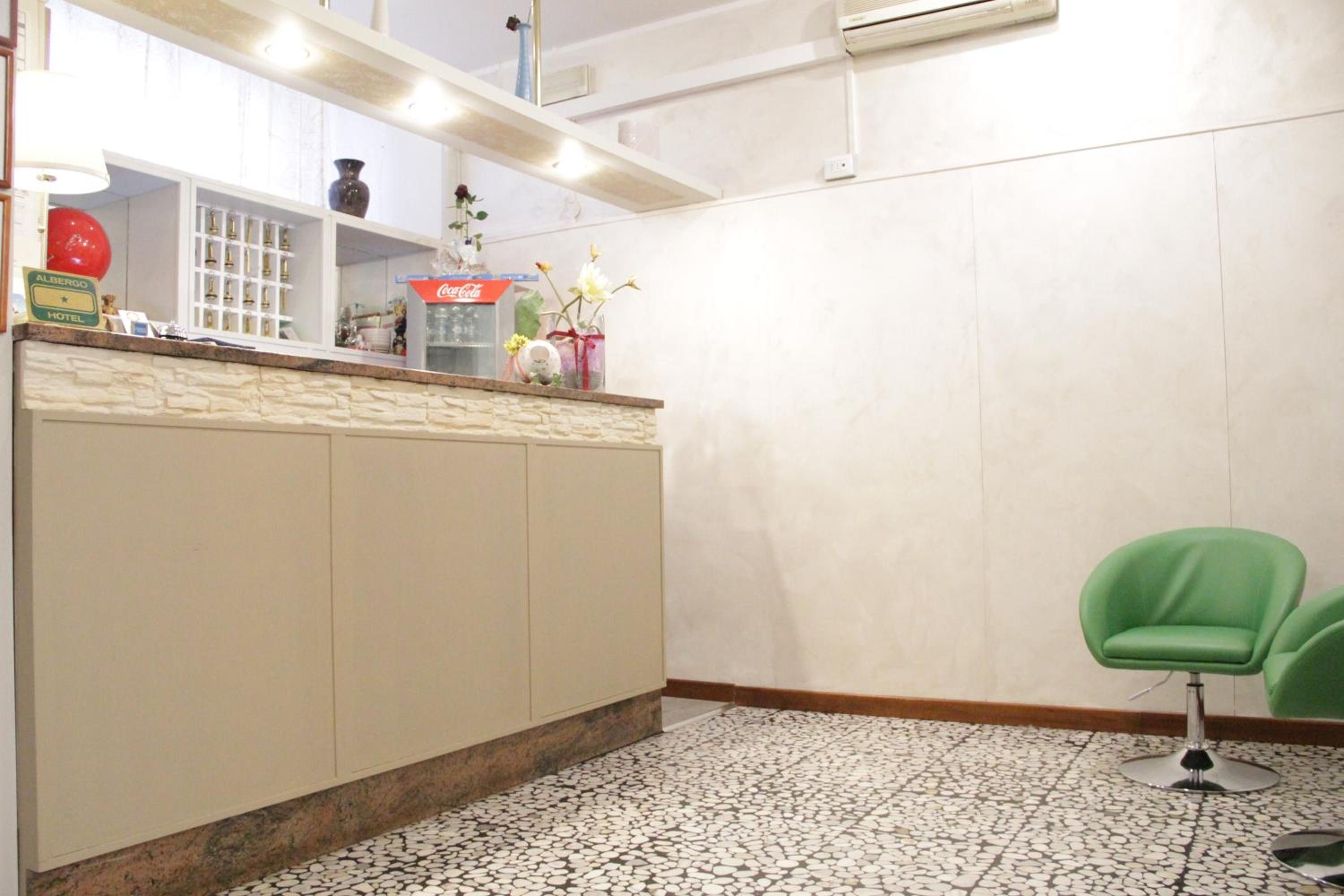 A reception area with a counter, a Coca-Cola refrigerator, and a green chair.