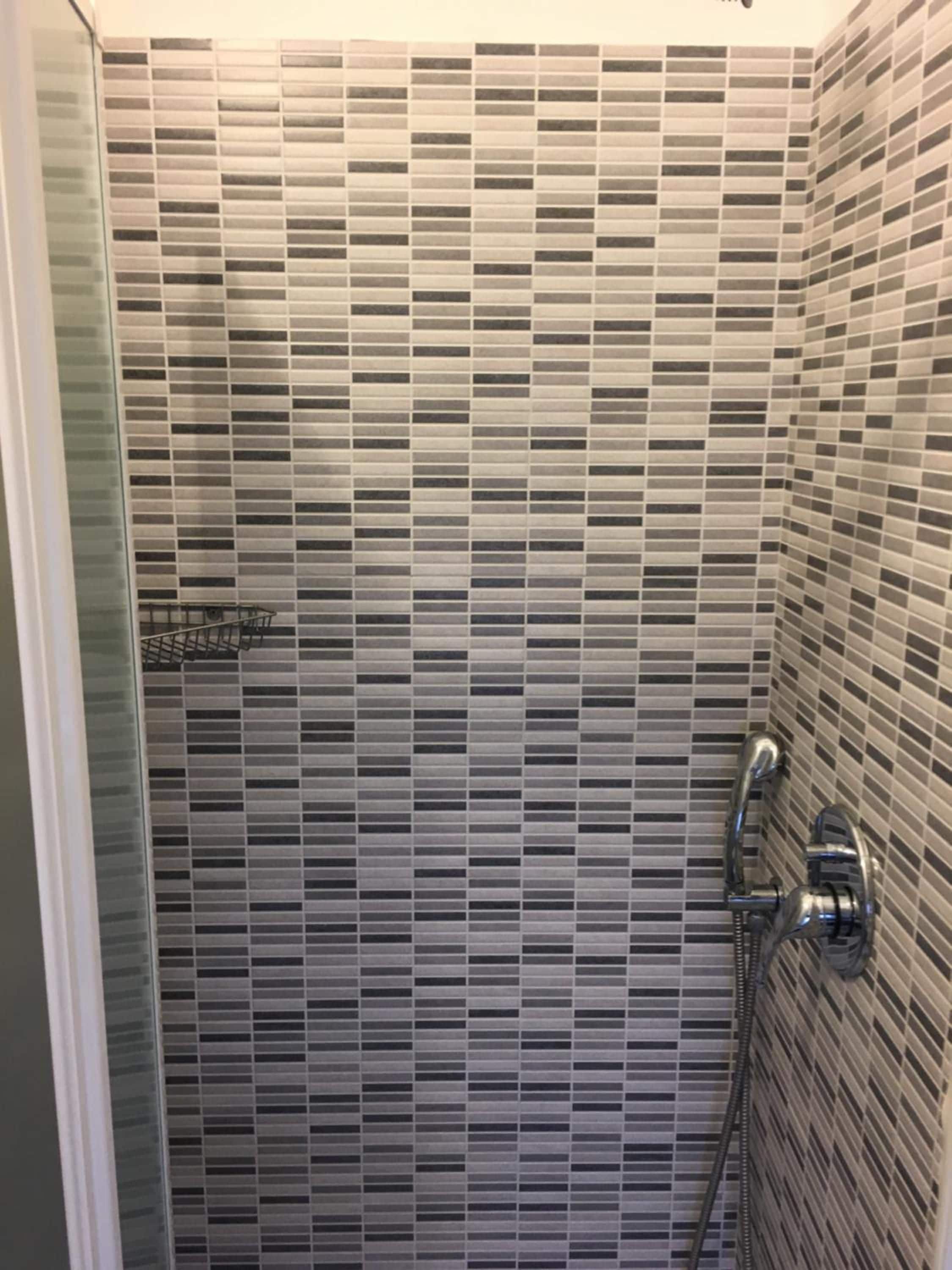 A shower area with a tiled wall and a showerhead.