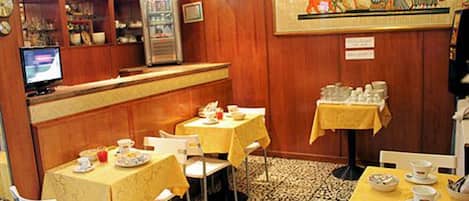 A restaurant with tables set for dining, a vending machine, and a decorative wall painting.