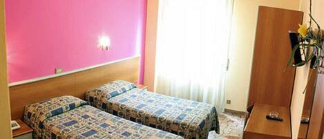 A room with two beds, a wooden wardrobe, and a window with curtains.