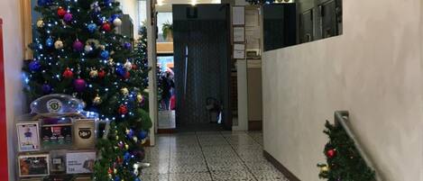 Una escalera con un árbol de Navidad decorado con adornos y luces de colores, que lleva a una habitación con piso de baldosas.