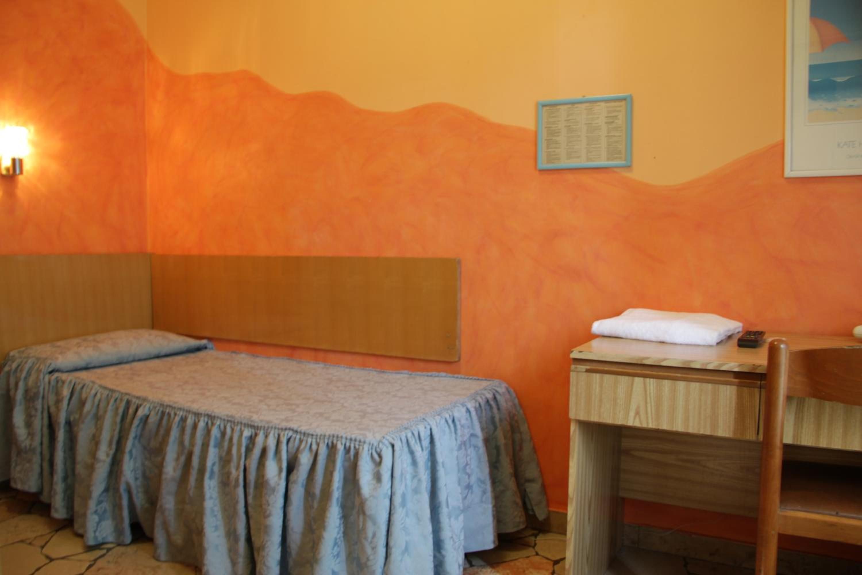 A room with two beds, a wooden desk, and a chair.