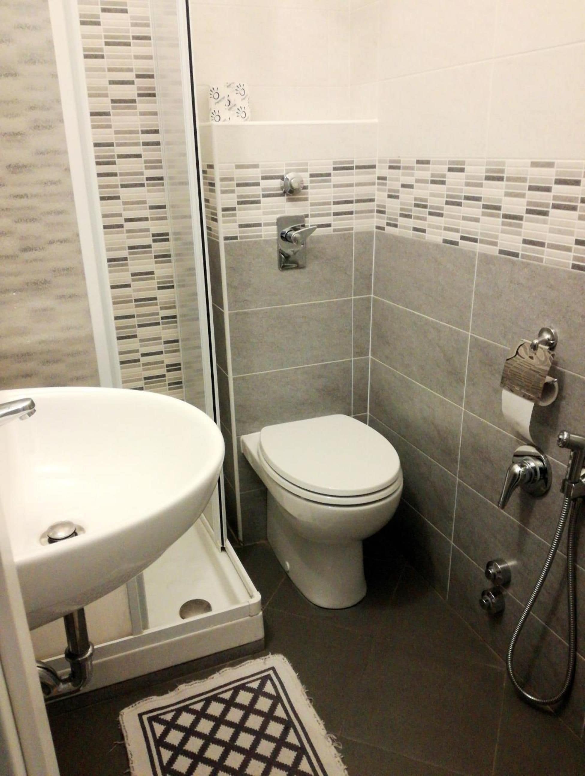 Une salle de bain avec un lavabo blanc, des toilettes et un espace douche.