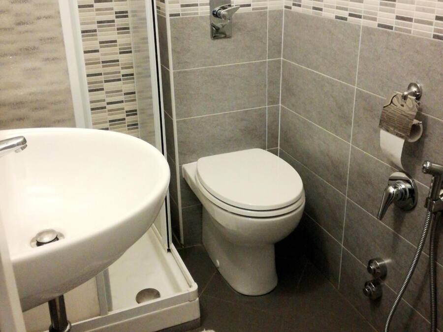 Casa de banho com lavatório branco, sanita e zona de duche.
