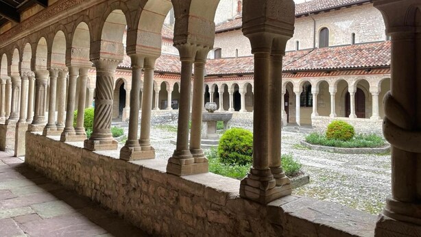 Une série d’arches en pierre, avec une cour en arrière-plan.