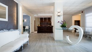 Eine moderne Lobby mit einem weißen Sofa, einem Empfangstresen und einem Glastisch mit Blumen.