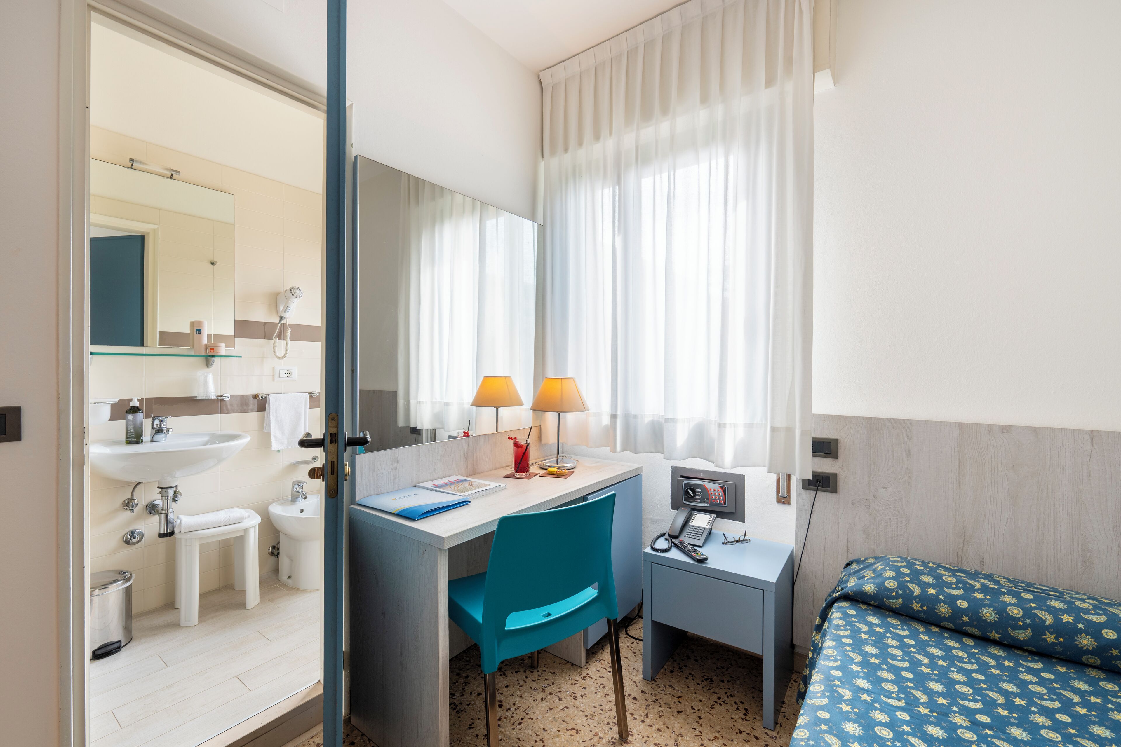 Une chambre d’hôtel comprenant une salle de bain, un bureau avec une chaise, un lit et un téléphone.
