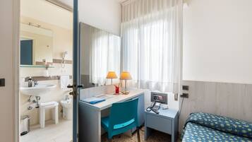 Une chambre d’hôtel comprenant une salle de bain, un bureau avec une chaise, un lit et un téléphone.