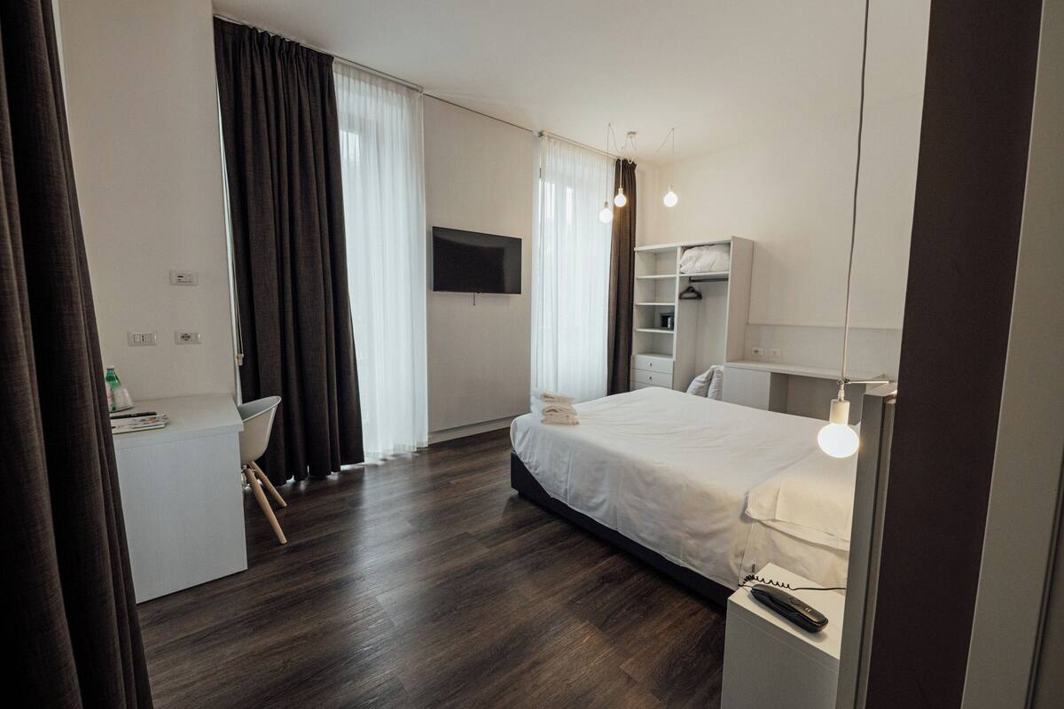Una habitación de hotel moderna con cama, escritorio y armario.