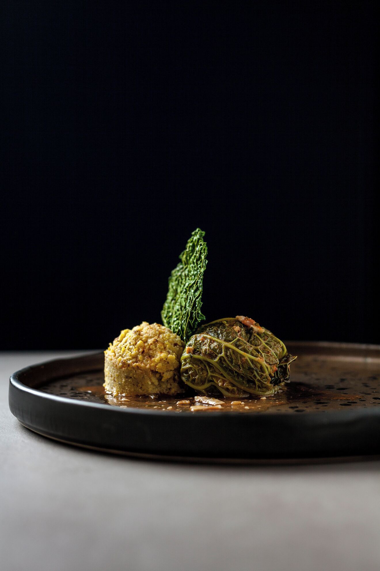 Un plato con dos verduras rellenas y una guarnición sobre un plato oscuro.