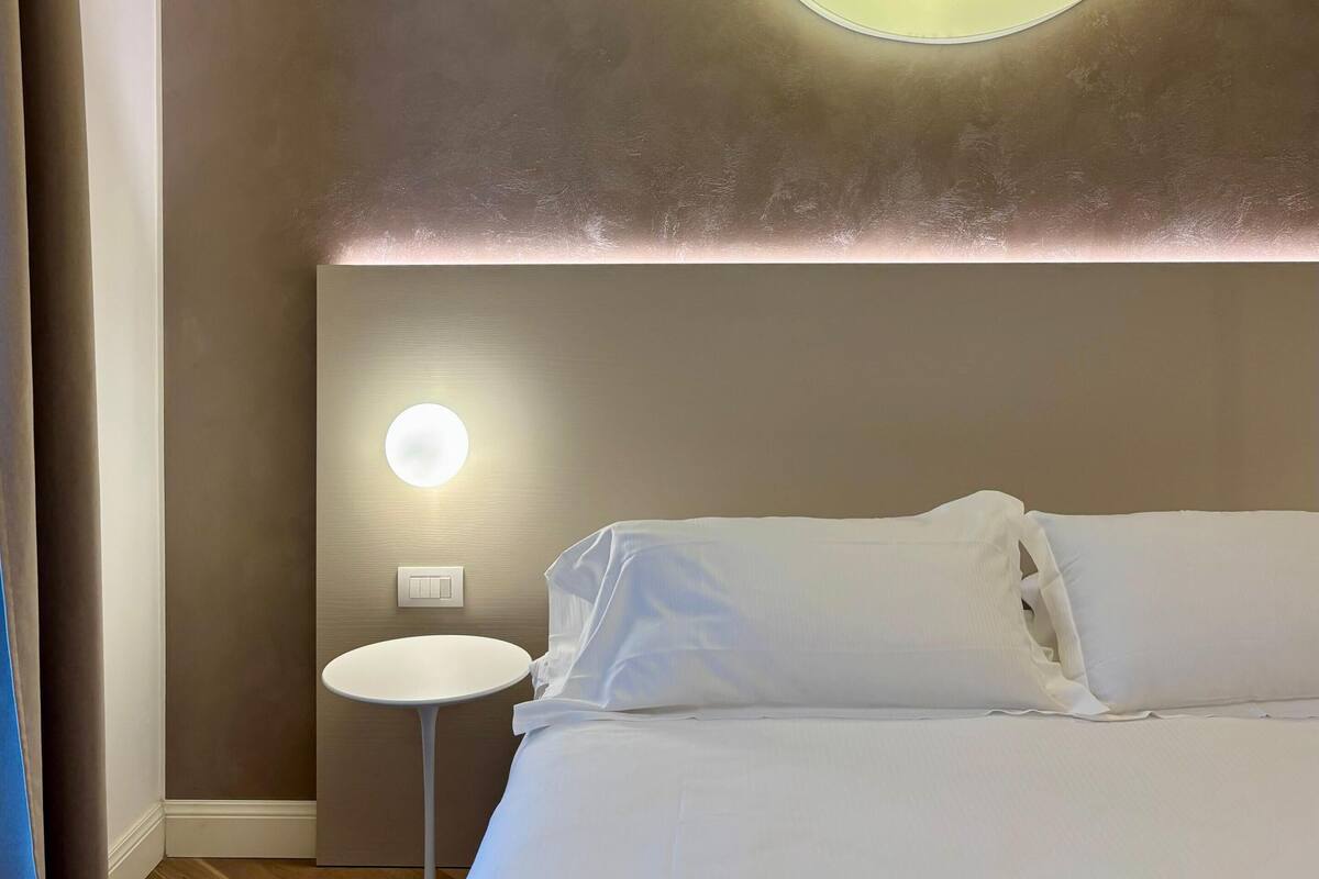 Un dormitorio con una cama, una mesita de noche, una lámpara de pared y una lámpara de techo con forma de luna creciente.