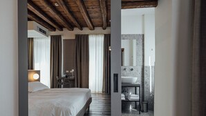 Une chambre d’hôtel moderne avec un plafond en bois, un grand lit, un bureau et une salle de bain dotée d’un comptoir en marbre.