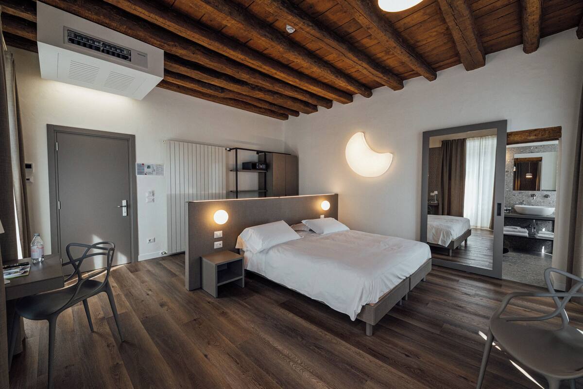 Un dormitorio moderno con techo de madera, una cama, mesitas de noche, un escritorio y una silla.