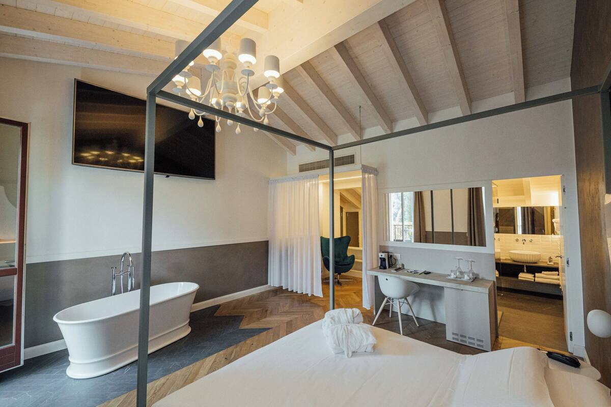 Una habitación de hotel moderna con una cama grande, un baño separado con bañera, un escritorio y una silla.