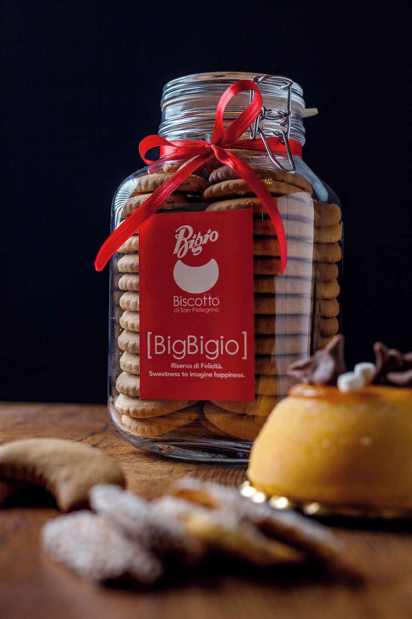Un barattolo di vetro con un nastro rosso e un'etichetta che riporta 'BigBigio Biscotto di San Pellegrino'.