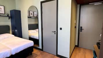 A bedroom with a bed, a wardrobe, a mirror, and a desk.
