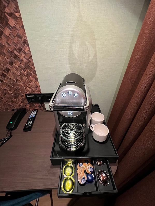 A coffee machine with a glass carafe, two white cups, and a tray with various coffee pods. - Hotel Nicolaas Witsen (Amsterdam)