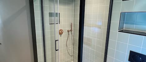 A modern bathroom with a glass-enclosed shower, checkered floor tiles, and a black toilet.