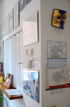 A wall with various informational posters, a map, and a door with a handle. - Alloggi Barbaria (Venice)