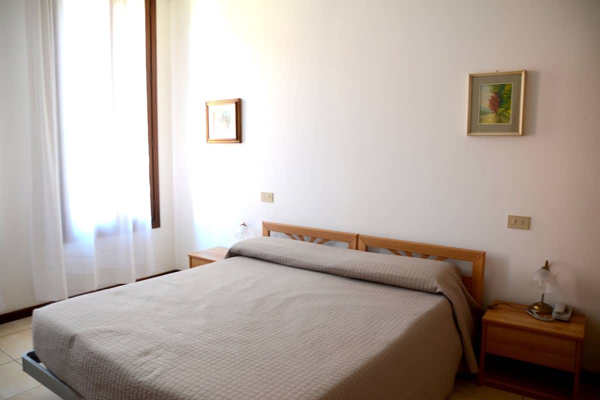 A bedroom with a bed, a nightstand, a lamp, and two framed pictures on the wall.
