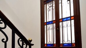 Una escalera con barandilla de madera y un vitral con diseños decorativos.