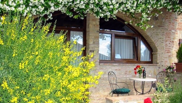 Ein Steinhaus mit einem Fenster und einem Tisch mit Stühlen davor.
