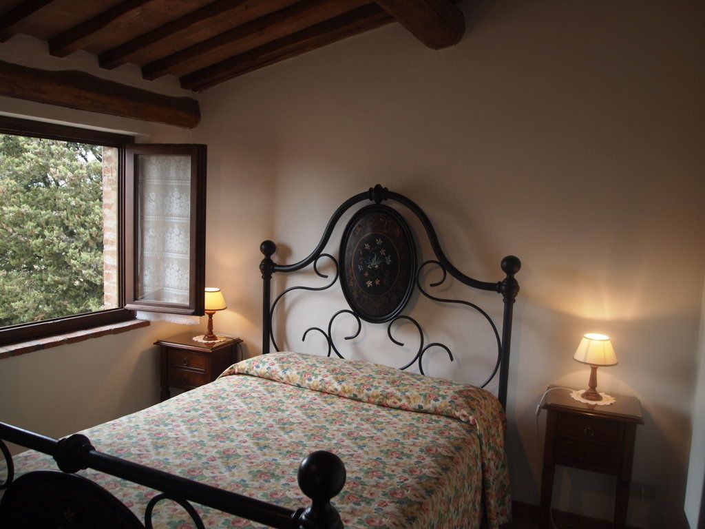 A bedroom with a bed, two bedside tables, a window, and a wall clock.