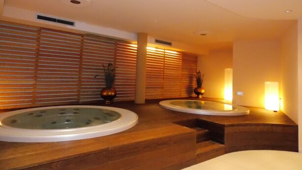 Een wellnessruimte met twee whirlpools en houten vloeren.