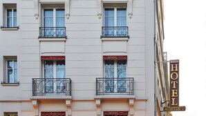 A building with two windows on the ground floor, each with a balcony and a sign above stating "HOTEL AUSTIN'S".