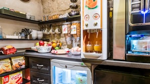 A kitchen with a refrigerator, a coffee machine, and a fruit bowl.