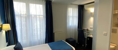 A hotel room with two beds, a bathroom, and a view of the outdoors.