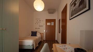 Una habitación de hotel con cama, escritorio, silla, lámpara de pared, un cuadro enmarcado y una cita motivacional en la pared.