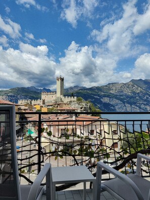 A balcony with a view of a historic tower and mountains. - Hotel Peler (Malcesine)