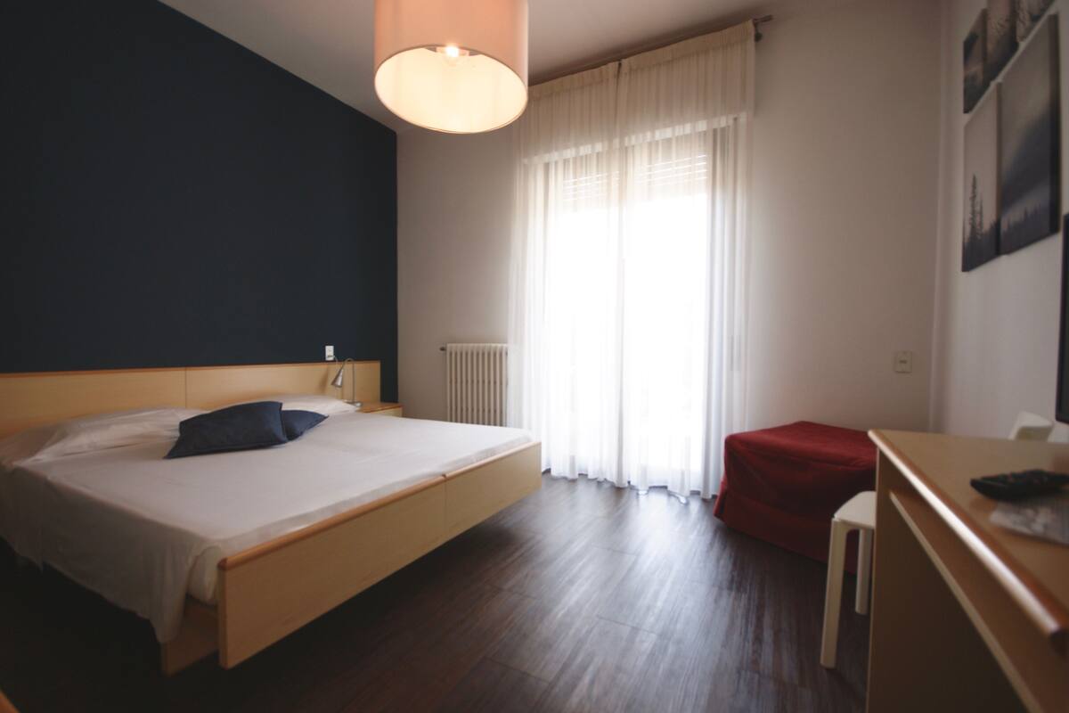 A bedroom with a bed, a desk, and a chair.
