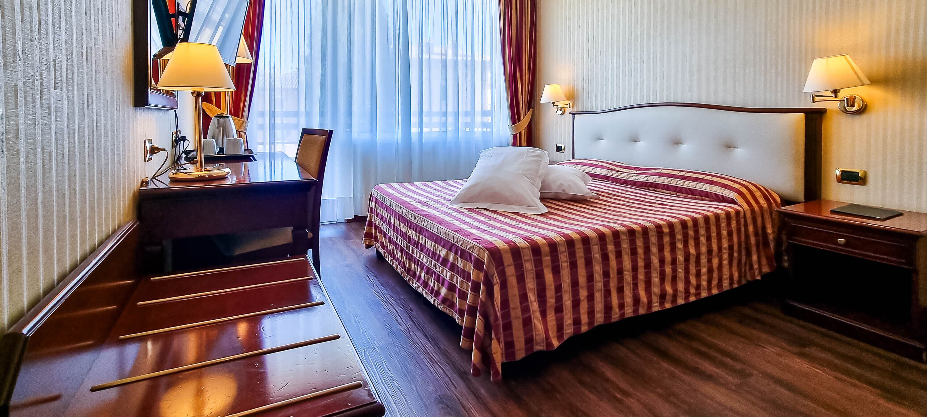 Una habitación de hotel con cama, mesitas de noche, escritorio y silla.