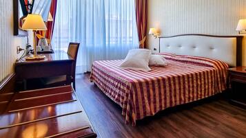 Una habitación de hotel con cama, mesitas de noche, escritorio y silla.
