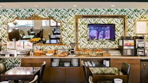 A breakfast area with a buffet setup, including coffee and tea stations, and a large mirror and television on the wall. - Benaco (Garda)