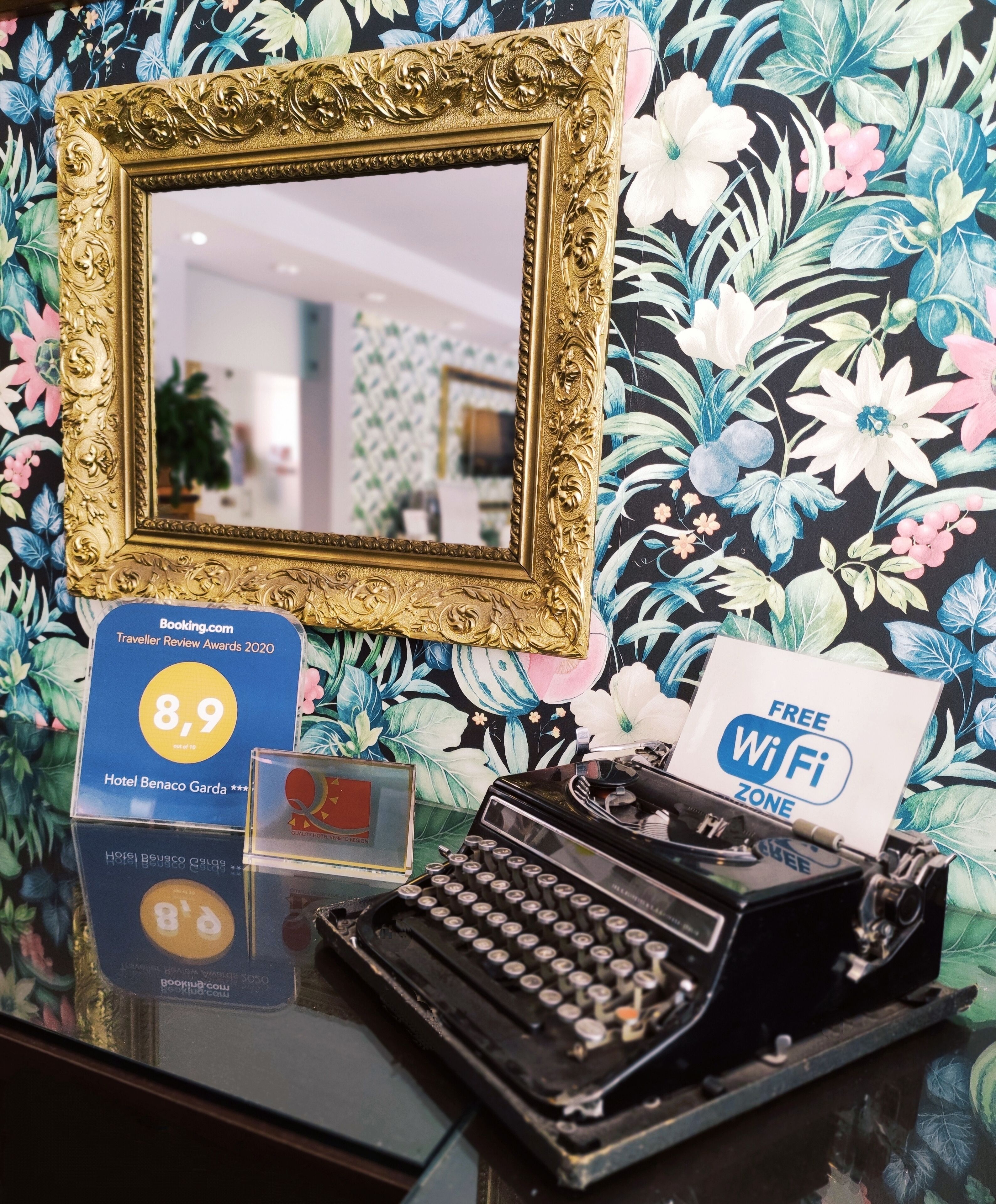 Una macchina da scrivere vintage, uno specchio incorniciato e un cartello con la valutazione per l'Hotel Benaco Garda.