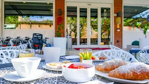 An outdoor café with a table set for two, featuring pastries, a drink, and a dessert. - Benaco (Garda)
