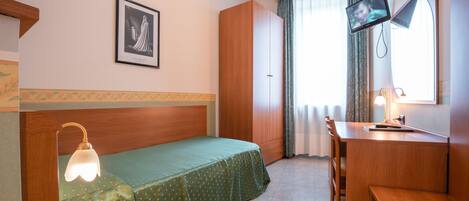 A hotel room with a bed, a desk, a chair, a television, and a window with curtains.