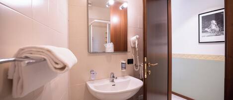 A bathroom with a sink, mirror, towel rack, and a door leading to another room.