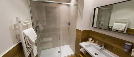 A modern bathroom with a glass-enclosed shower, a sink, and a mirror.
