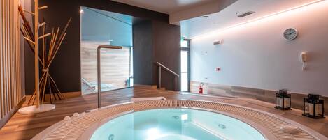 A modern spa area with a hot tub, wooden flooring, and minimalist decor.