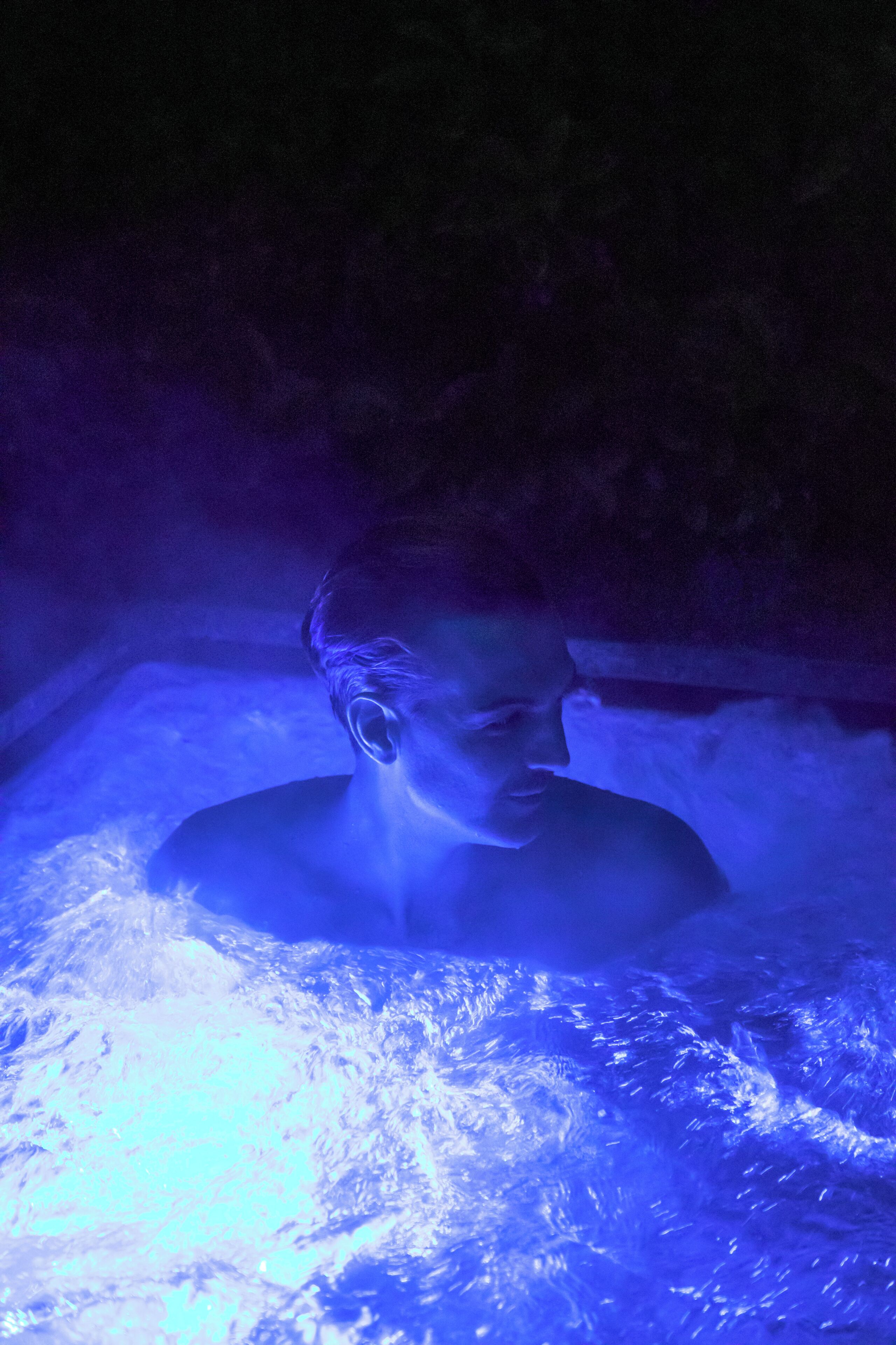 Eine Person in einem Whirlpool bei blauem Licht.