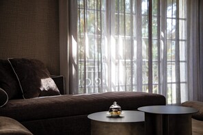 A modern living room with a sofa, a round coffee table, and a glass display case with a decorative item. - Magdalenerhof (Bolzano)