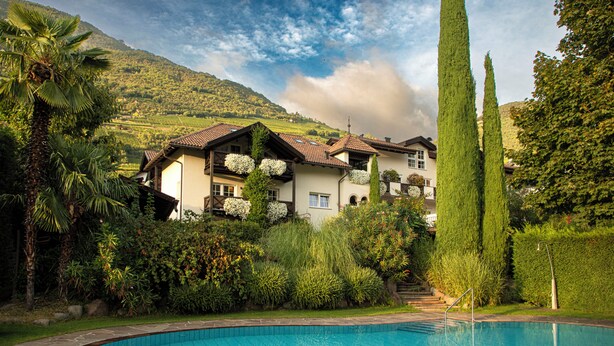 A house with a swimming pool, surrounded by lush greenery and a mountain in the background. - Magdalenerhof (Bolzano)
