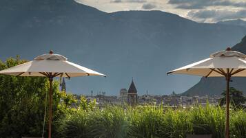Relax by the serene pool surrounded by lush greenery and a stunning cityscape.